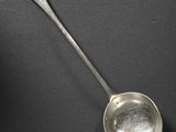 une cuillère en argent dont le manche repose sur une surface noire
