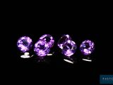 un groupe de pierres précieuses violettes posées sur une surface noire