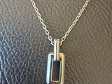 a close up of a silver necklace with a bottle on it