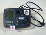 une calculatrice reliée à un cordon, posée sur une table