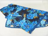 a blue scarf with blue flowers on it on a white surface