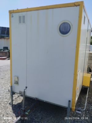 une photo représentant des toilettes portables blanches et jaunes dans un parking