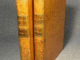 two old books sitting on top of each other on a table