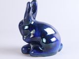 a small blue rabbit statue sitting on a white surface