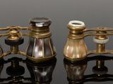 three antique brass binoculars are sitting on a black surface