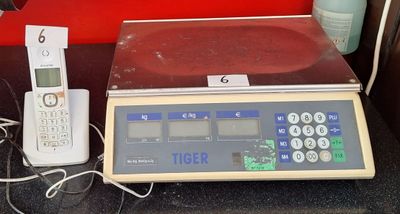 une balance numérique, un téléphone portable et un téléphone fixe posés sur la table