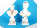 une paire de bustes en marbre blanc représentant un homme et une femme, sur fond bleu