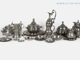une assiette en argent et des couverts en argent sur fond blanc