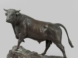 statue of a bull standing on a rock on a gray background