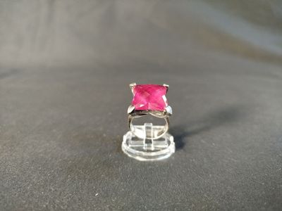 a pink stone ring sitting on top of a glass stand