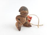 une petite figurine posée sur une surface blanche, avec une ficelle