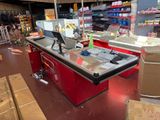 a red counter in a store with a computer on top of it