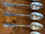 six silver spoons are lined up on a wooden table