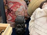 une poupée avec un chapeau et un appareil photo, à côté d'une vitrine
