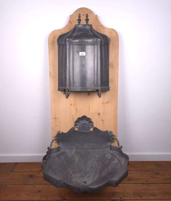 fontaine ancienne en fonte posée sur un socle en bois, dans une pièce aux murs blancs