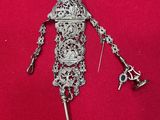 an image of a silver broochle with a key attached to it