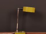 a yellow table lamp on a wooden table with a black wall behind it