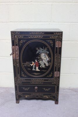 une photo d'une armoire noire sur laquelle est accrochée une peinture