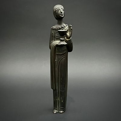 une ancienne statue en bronze représentant une femme tenant un livre
