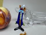 a figurine of a clown standing next to a glass vase