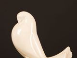 a white sculpture of a bird sitting on a table