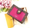 a pink and brown wallet sitting on a box next to a pink flower