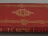 an old red book sitting on top of a white table