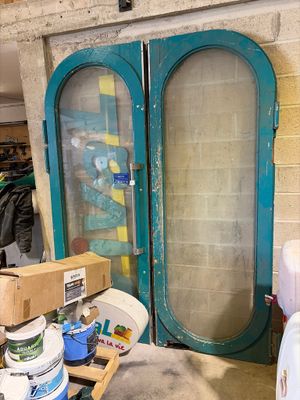 two large green doors in a room with a lot of stuff