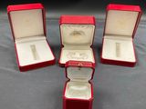 trois boîtes rouges contenant chacune une bague, posées sur une table