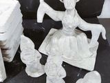 a statue of a woman sitting on a chair surrounded by figurines