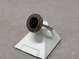 a close up of a silver ring with a green stone on it