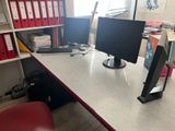 a desk with two computer monitors on it and a red chair in front of it