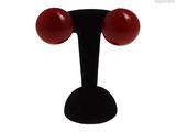 un gros plan sur une paire de boucles d'oreilles rouges posées sur un support noir