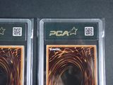 pair of two pca trading cards in plastic cases on a table