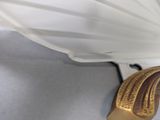 a white lamp with a gold handle on the wall
