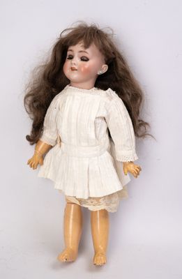 une vieille poupée en porcelaine aux longs cheveux, vêtue d'une robe blanche
