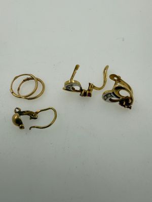 three pairs of gold and silver earrings on a white surface