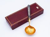 a gold spoon with a black handle sitting on top of a box