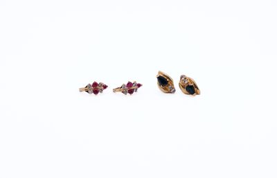 two pairs of gold and ruby earrings on a white background