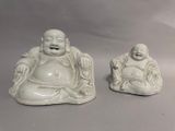 two statues of laughing buddhas sitting on a table