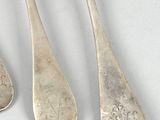 three silver spoons and two silver spoons sitting next to each other