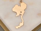 a close up of a gold pendant on a marble surface