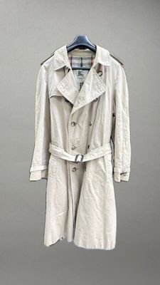 un trench-coat beige suspendu à un cintre contre un mur gris