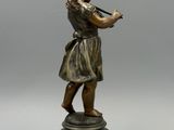 une figurine antique en bronze représentant une jeune fille jouant de la flûte