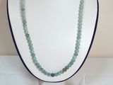 Ensemble collier et boucles d'oreilles avec des perles de verre vertes, présenté sur un mannequin blanc