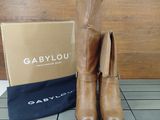 tan leather boots with tassels on the heel and a box on the floor