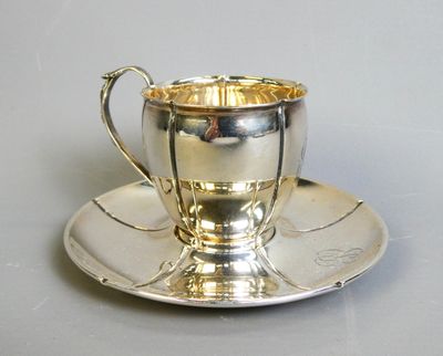 a silver cup and saucer sitting on a saucer