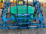 a blue tractor with a green tank attached to the back of it