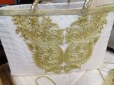 a white bag with gold embroidery on it sitting on a table