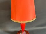une lampe orange avec un abat-jour rouge posée sur un socle en bois